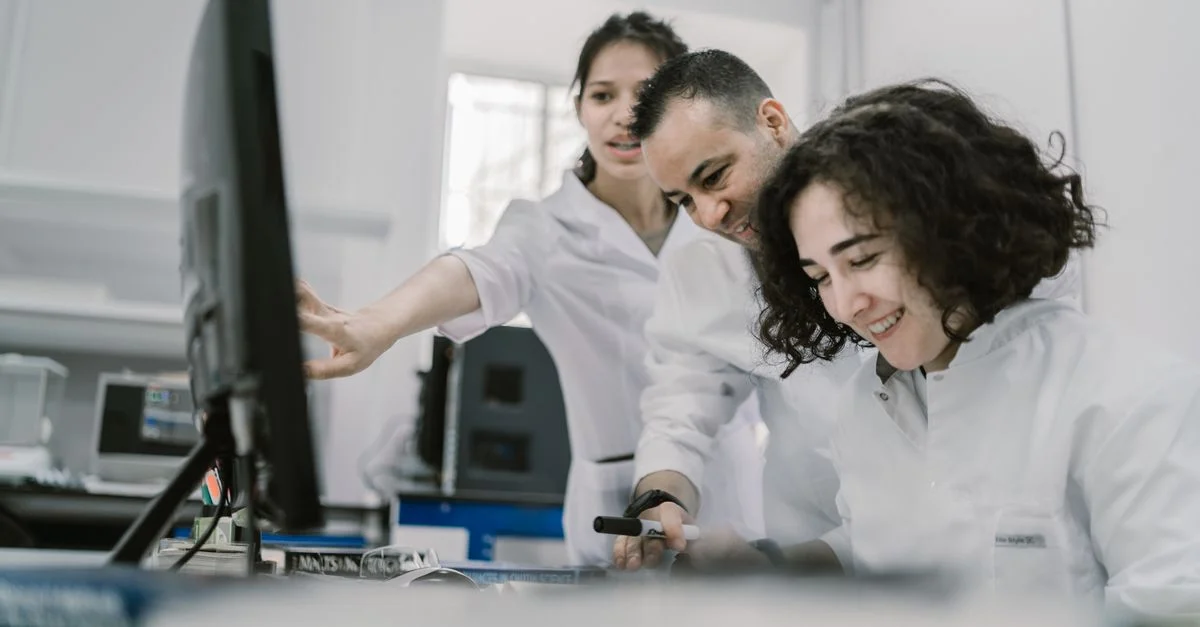 Groupe de scientifiques divers travaillant ensemble sur un ordinateur dans un laboratoire moderne et lumineux.