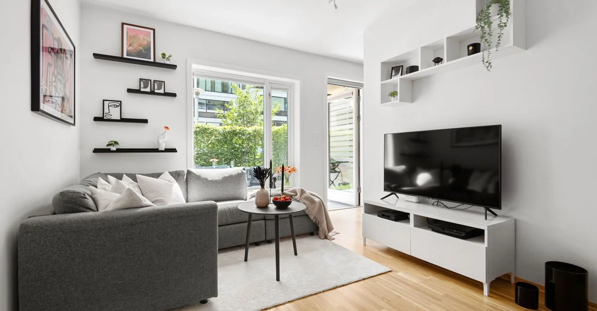 Salon moderne élégant avec canapé gris, murs blancs et décoration épurée.