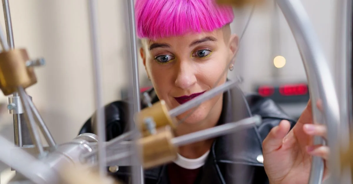 Une jeune femme curieuse aux cheveux roses examine du matériel scientifique dans un environnement de laboratoire.