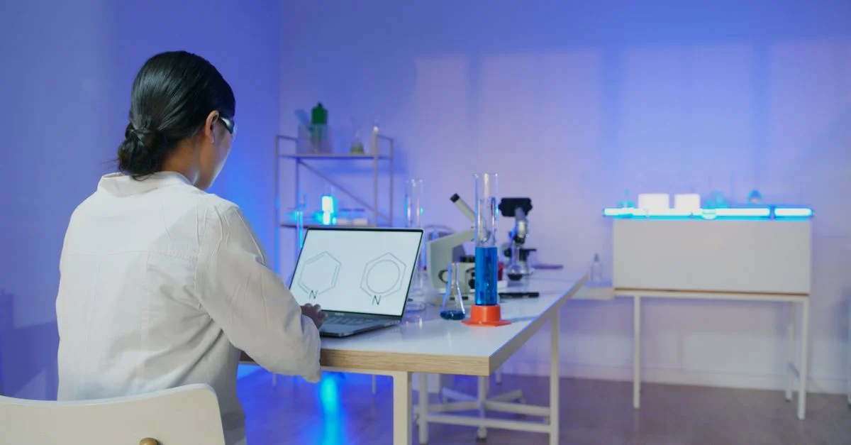 Scientifique féminine étudiant des structures chimiques sur un ordinateur portable dans un laboratoire moderne.