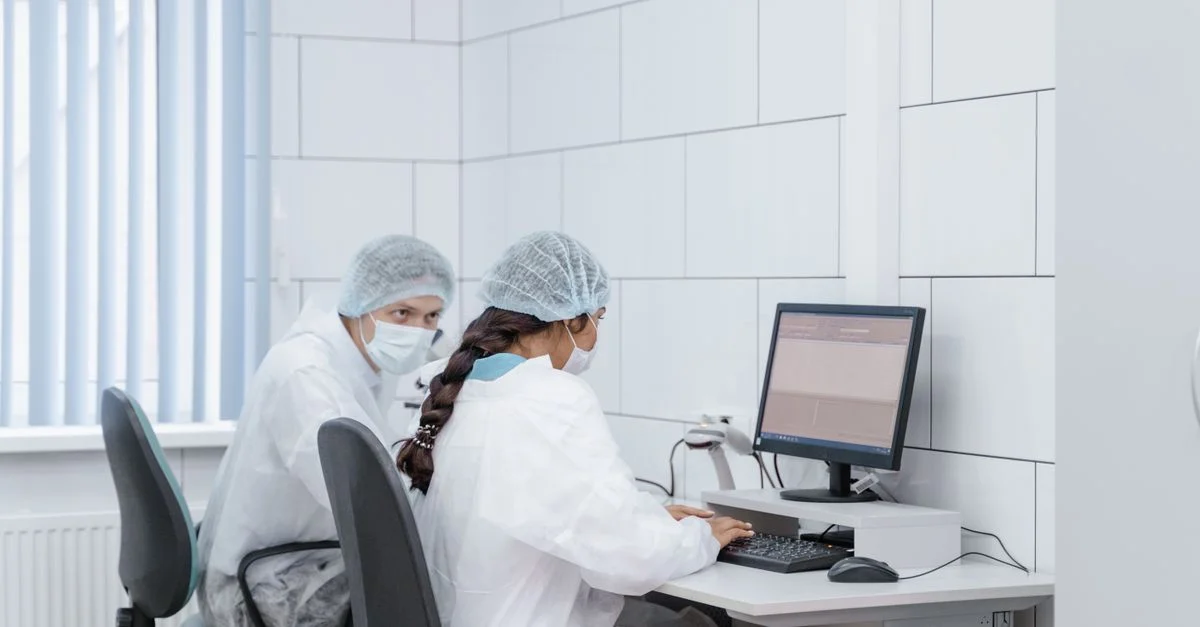 Deux scientifiques devant un ordinateur dans un environnement de laboratoire, analysant des données avec concentration et précision.