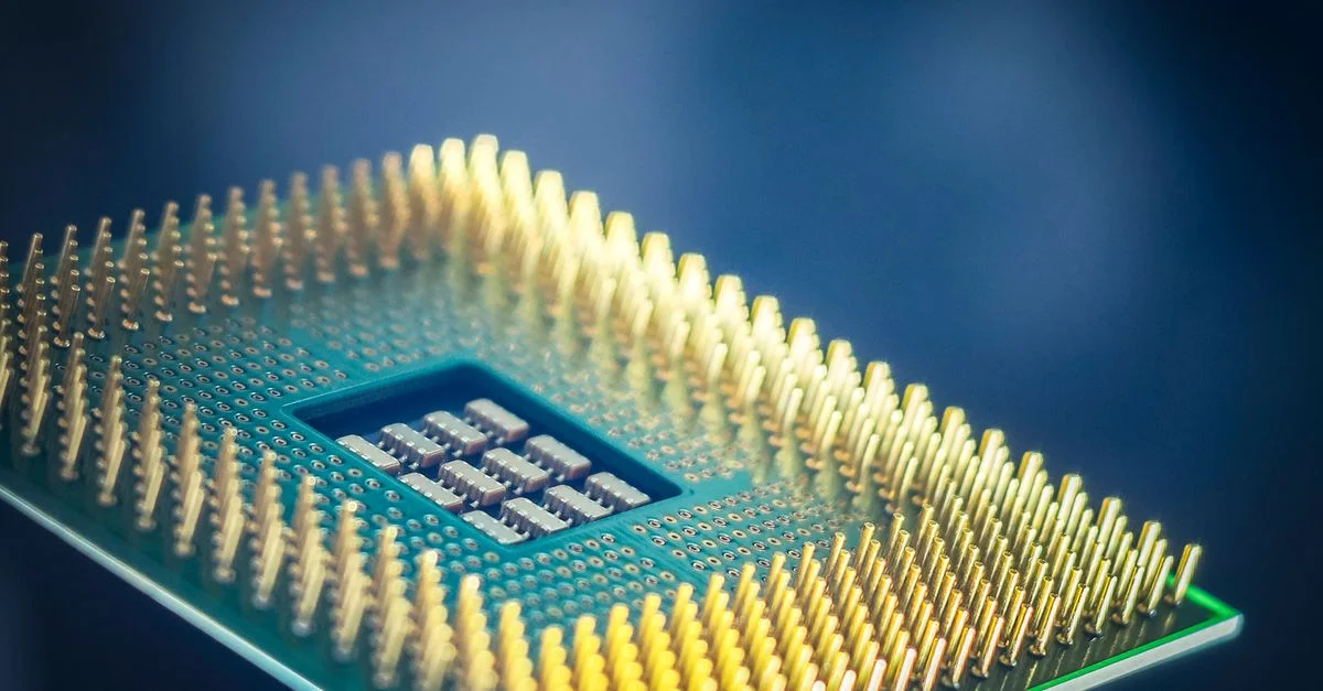 Photo macro haute résolution d'une puce de processeur d'ordinateur avec des broches dorées sur fond bleu.