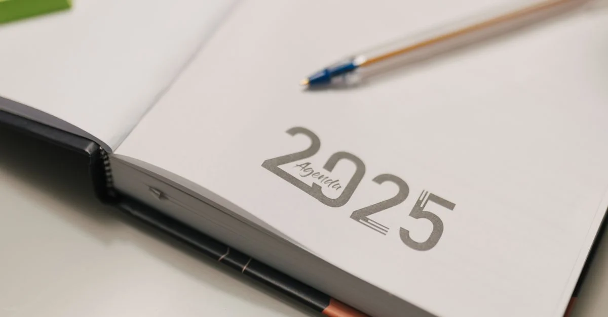 Livre d'agenda 2025 ouvert avec un stylo bleu sur un bureau, idéal pour l'organisation et la planification.