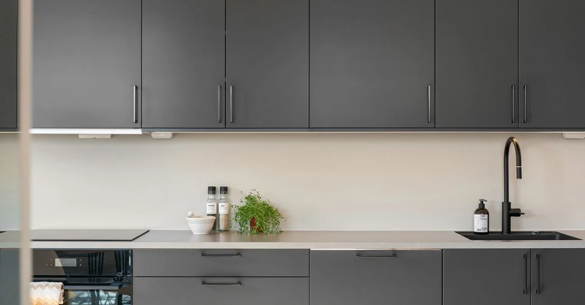 Une cuisine moderne et épurée avec des armoires sombres, un design minimaliste et une décoration élégante.